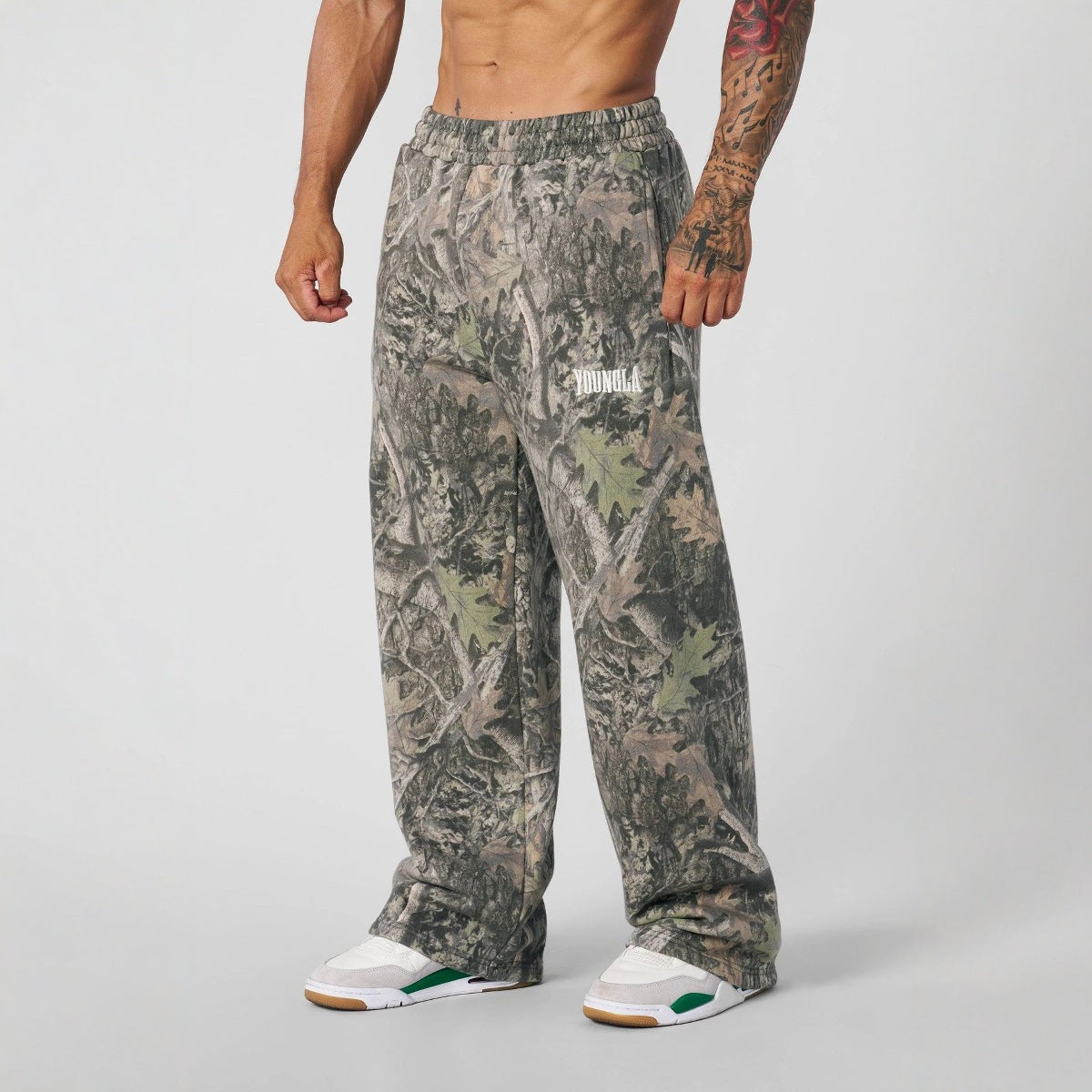 Camouflage pants worn by a person on a plain background